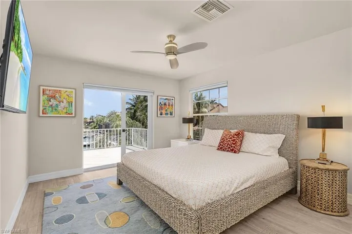 Bedroom with access to exterior, wood finished floors, and a ceiling fan