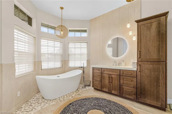 Bathroom with a freestanding bath, healthy amount of natural light, vanity, tile walls, and a wainscoted wall