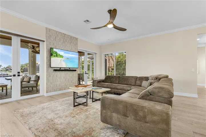 Living area featuring french doors, ceiling fan, light wood-style floors, and ornamental molding