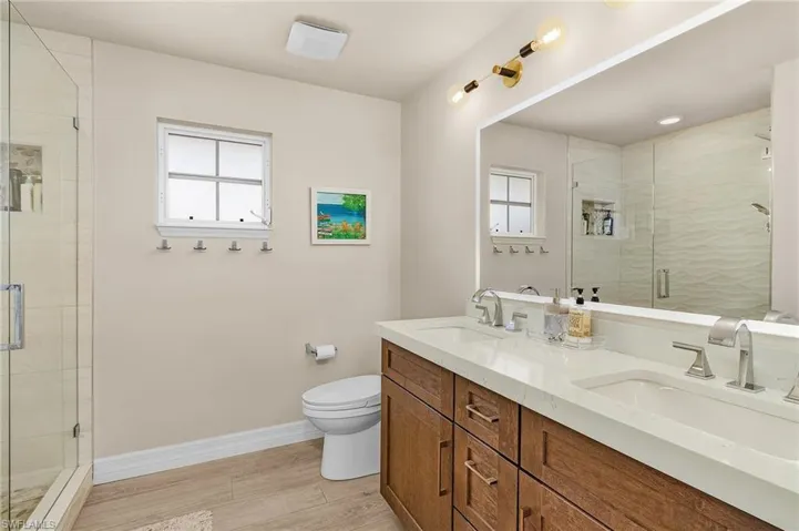 Full bath with plenty of natural light, double vanity, and a stall shower