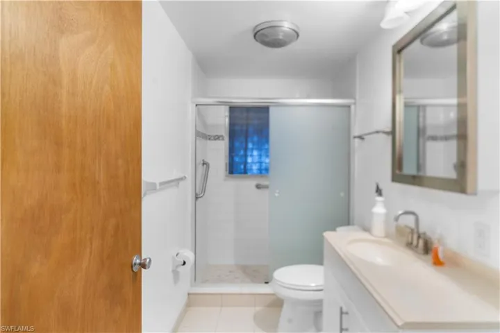 Bathroom with tile patterned floors, a shower with door, vanity, and toilet