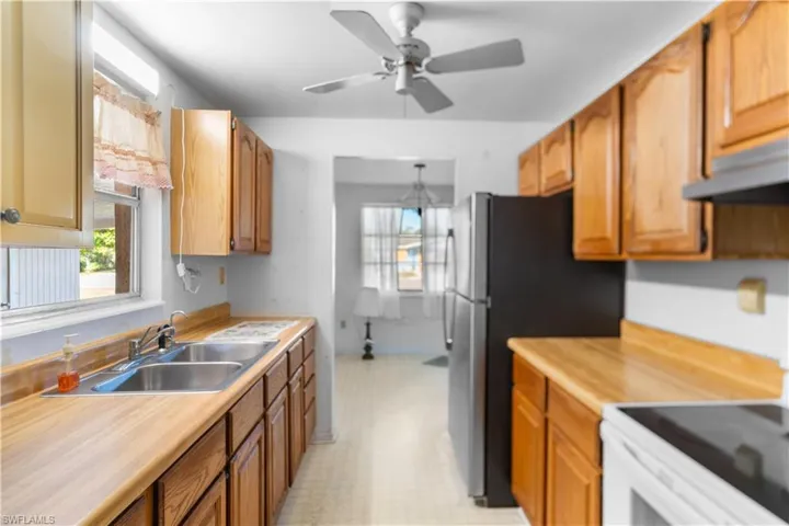 Kitchen with stainless steel fridge, ceiling fan, sink, and white electric range oven