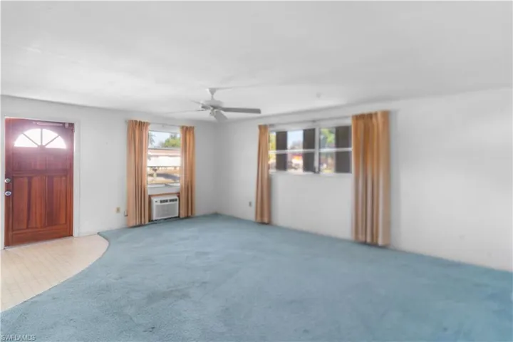 Unfurnished living room featuring carpet, ceiling fan, and cooling unit