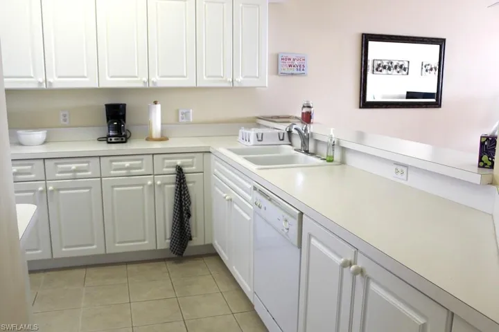 Kitchen with white cabinets, light countertops, dishwasher, and light tile patterned flooring