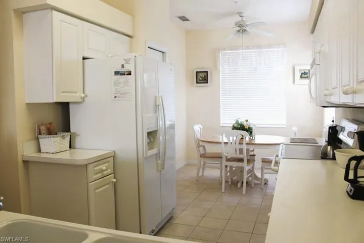 Kitchen featuring light countertops, white appliances, light tile patterned flooring, and white cabinets