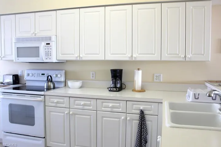 Kitchen with white appliances, light countertops, and white cabinets