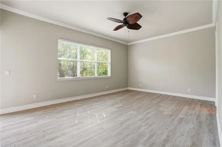 Spare room featuring ceiling fan, ornamental molding, and light wood-style floors