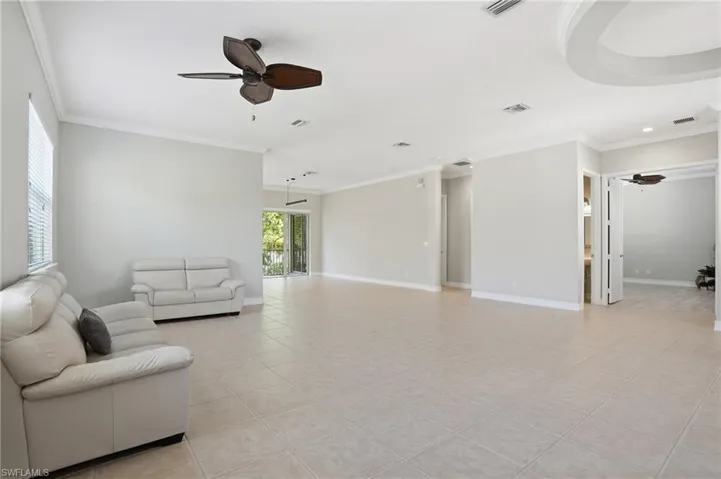 Living room featuring ceiling fan, light tile patterned flooring, and crown molding