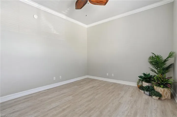 Empty room with crown molding, light wood-type flooring, and ceiling fan