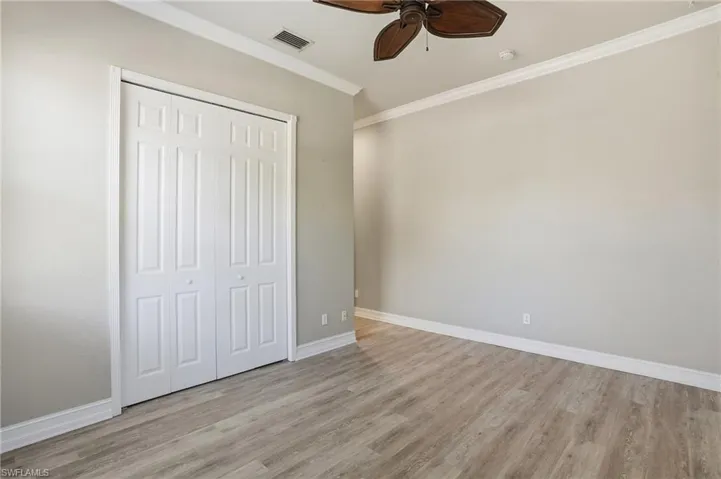 Unfurnished bedroom with crown molding, a ceiling fan, light wood-type flooring, and a closet