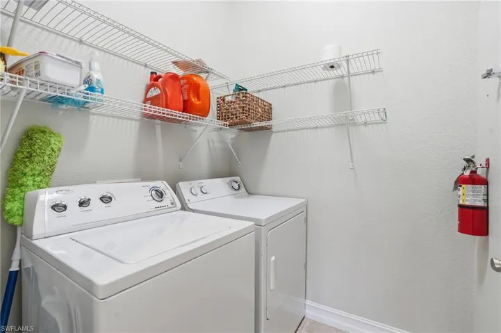 Laundry room featuring a textured wall and washer and clothes dryer