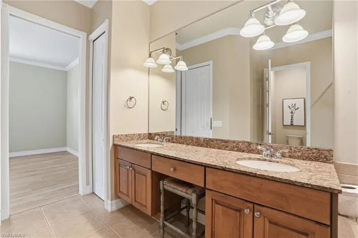 Bathroom featuring ornamental molding, double vanity, and light tile patterned flooring