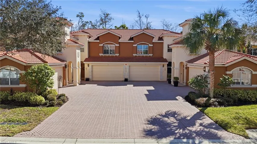 Mediterranean / spanish-style house featuring a tiled roof, an attached garage, stucco siding, and decorative driveway