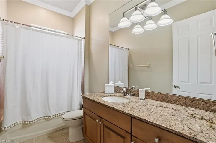 Full bath with crown molding, vanity, shower / tub combo with curtain, and light tile patterned flooring