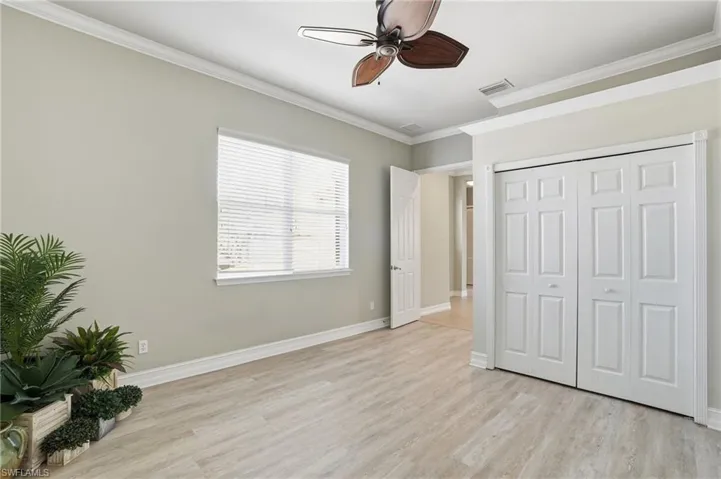 Unfurnished bedroom featuring ornamental molding, light wood-style floors, a closet, and ceiling fan