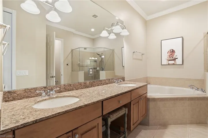 Full bath with double vanity, a garden tub, crown molding, light tile patterned flooring, and a stall shower