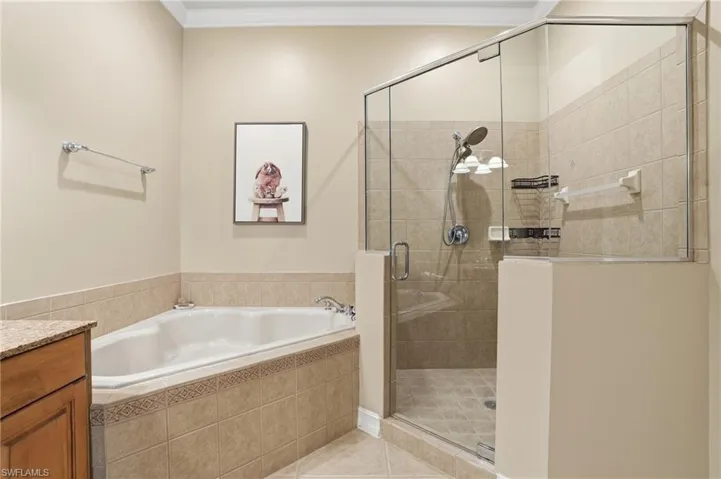 Bathroom featuring a shower stall, a bath, vanity, light tile patterned flooring, and crown molding