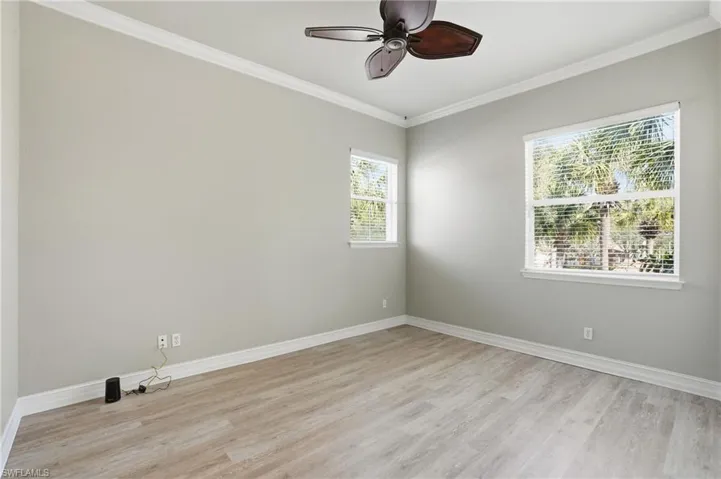 Unfurnished room with light wood-style floors, ornamental molding, and ceiling fan