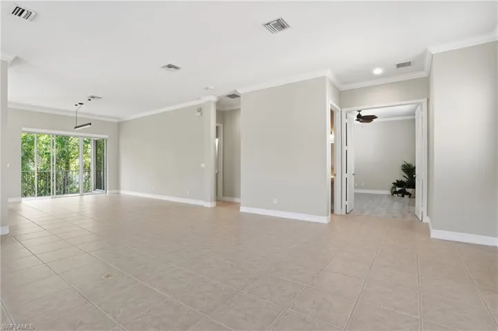 Empty room featuring ornamental molding, light tile patterned flooring, and a ceiling fan
