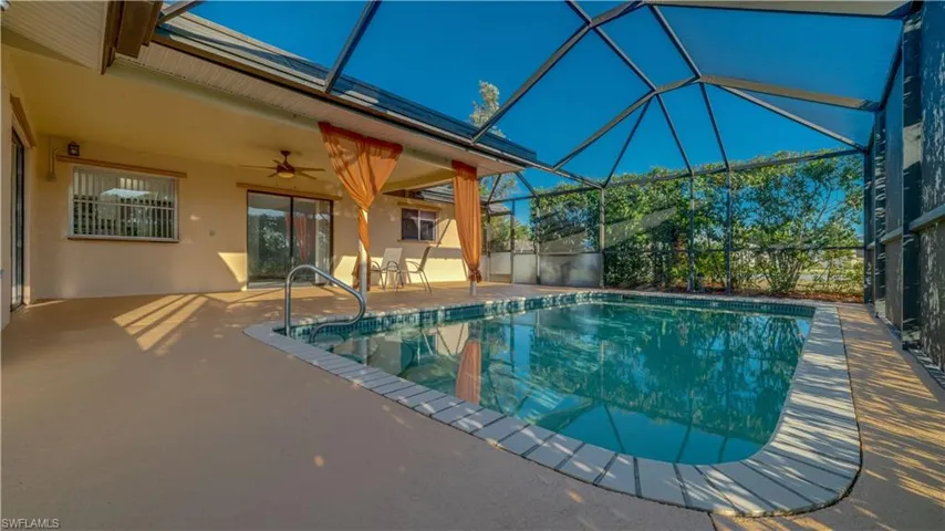 View of pool with ceiling fan, glass enclosure, and a patio