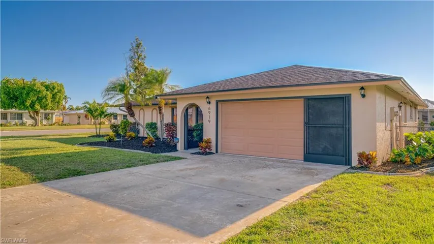 Ranch-style house featuring a garage and a front lawn