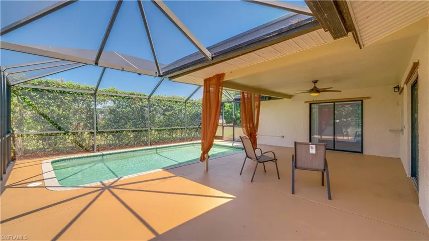 View of pool featuring ceiling fan, glass enclosure, and a patio