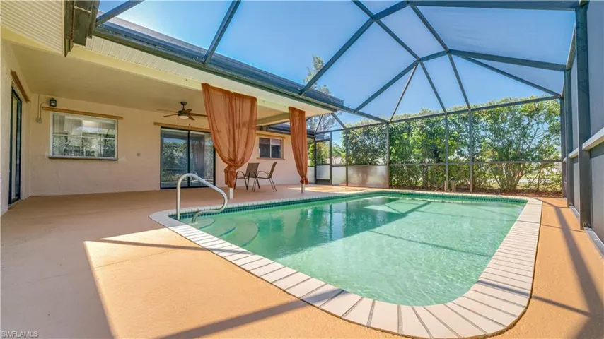 View of pool featuring ceiling fan, glass enclosure, and a patio