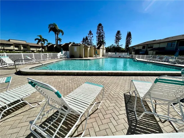 Community pool with a patio area and fence