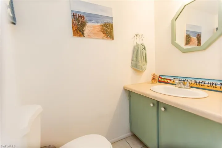 Half bathroom featuring vanity, toilet, baseboards, and tile patterned flooring