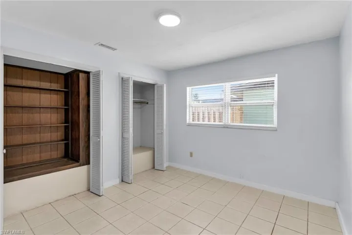 Unfurnished bedroom featuring multiple closets and light tile patterned flooring