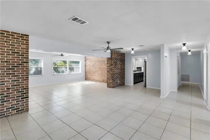 Unfurnished living room featuring light tile patterned floors and brick wall