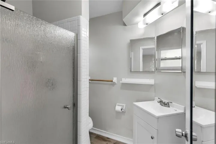 Bathroom with toilet, vanity, a shower with shower door, and hardwood / wood-style flooring