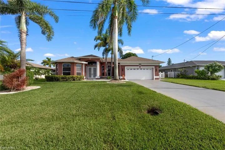 View of exterior entry featuring a garage and a lawn
