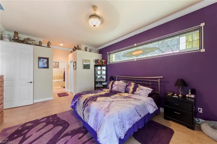 Bedroom with crown molding, connected bathroom, light tile patterned floors, and ceiling fan
