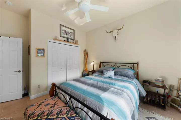 Tiled bedroom with ceiling fan and a closet