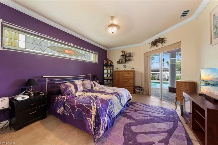 Bedroom with ceiling fan, light tile patterned floors, access to exterior, and ornamental molding