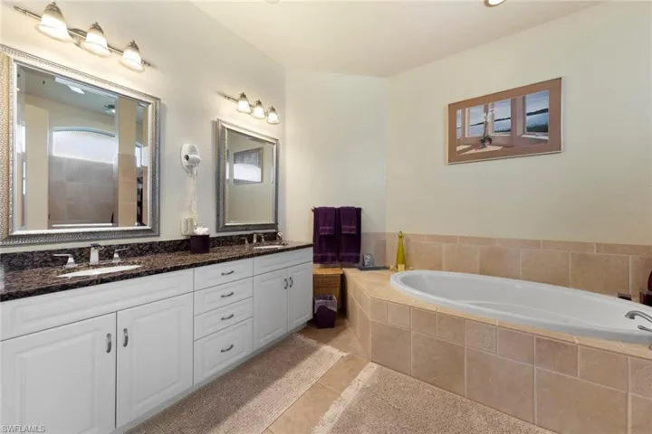 Bathroom with tile patterned flooring, tiled bath, and vanity