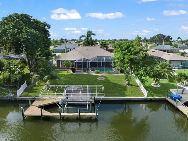 Dock area with a lanai, a swimming pool, a lawn, and a water view