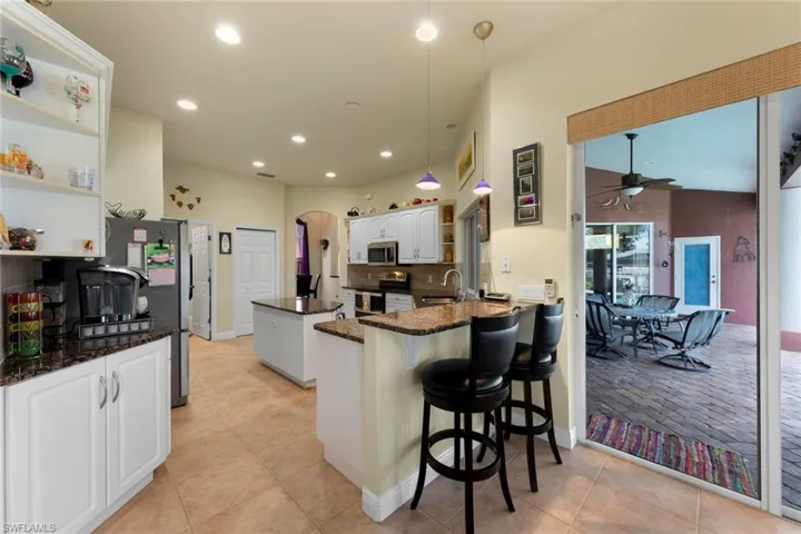 Kitchen with stainless steel appliances, kitchen peninsula, ceiling fan, hanging light fixtures, and a breakfast bar area