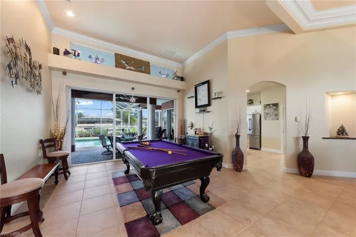 Recreation room with crown molding, a high ceiling, light tile patterned floors, and pool table