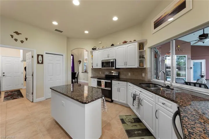 Kitchen featuring ceiling fan, stainless steel appliances, white cabinetry, and sink