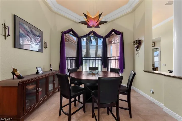 Tiled dining area with crown molding and a tray ceiling