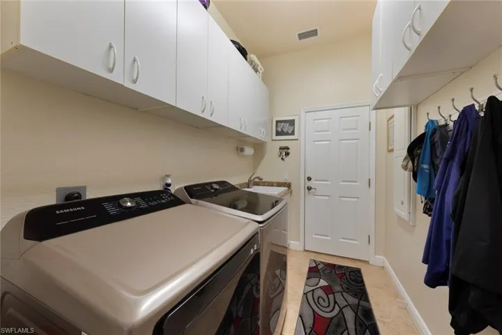 Laundry area featuring light tile patterned floors, cabinets, and washer and clothes dryer