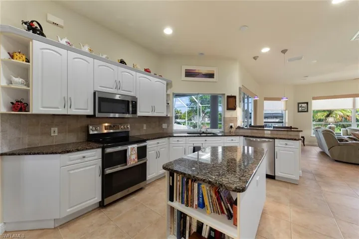 Kitchen with white cabinets, appliances with stainless steel finishes, kitchen peninsula, and a healthy amount of sunlight