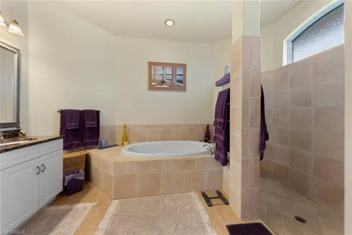 Bathroom featuring vanity, shower with separate bathtub, and tile patterned flooring