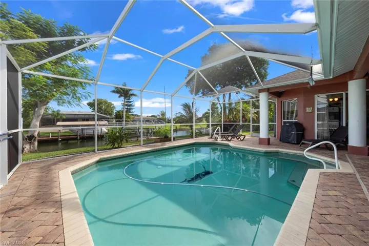 View of pool with a water view, grilling area, a patio area, and glass enclosure