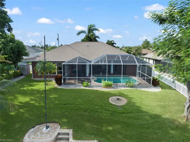 Rear view of property featuring a fenced in pool, a yard, a patio, and a lanai