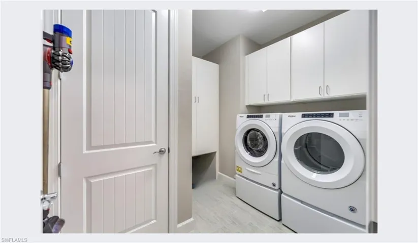 Clothes washing area featuring cabinets and washing machine and clothes dryer