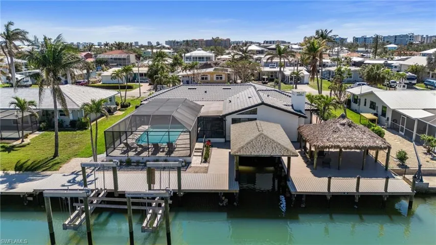 The outdoor oasis includes the spacious pool with a spa, massive covered area under the thatch roof and also two boat docks, one with a lift.  (Photo digitally enhanced)