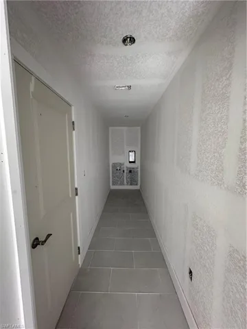 Hall featuring a textured ceiling and light tile patterned floors